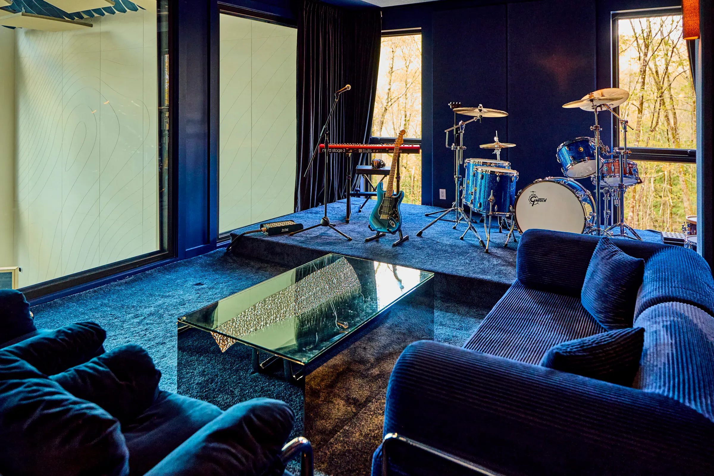 Lounge seating area at Verdant Sound — blue velvet sofas and glass coffee table facing the stage